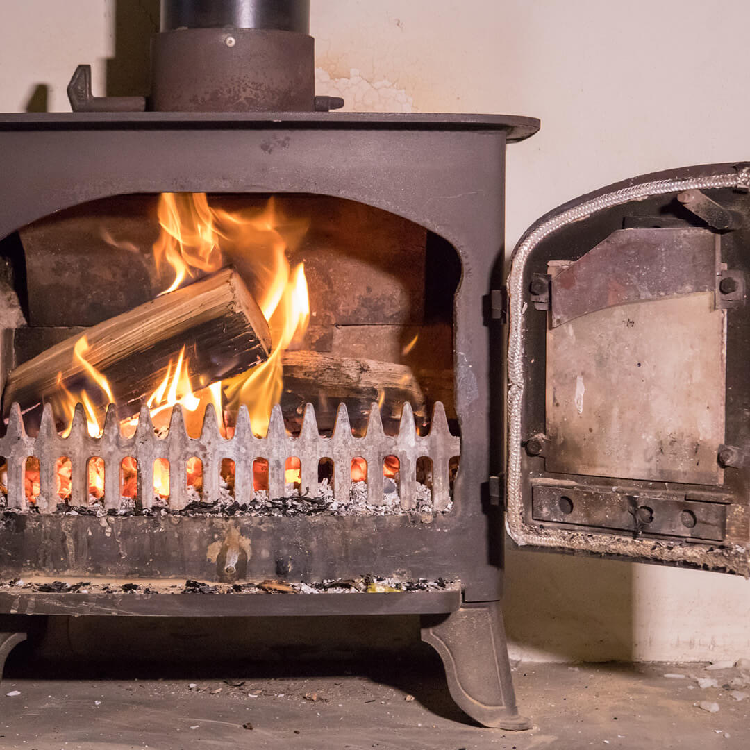 Old, not clean-burning wood stove with open doors