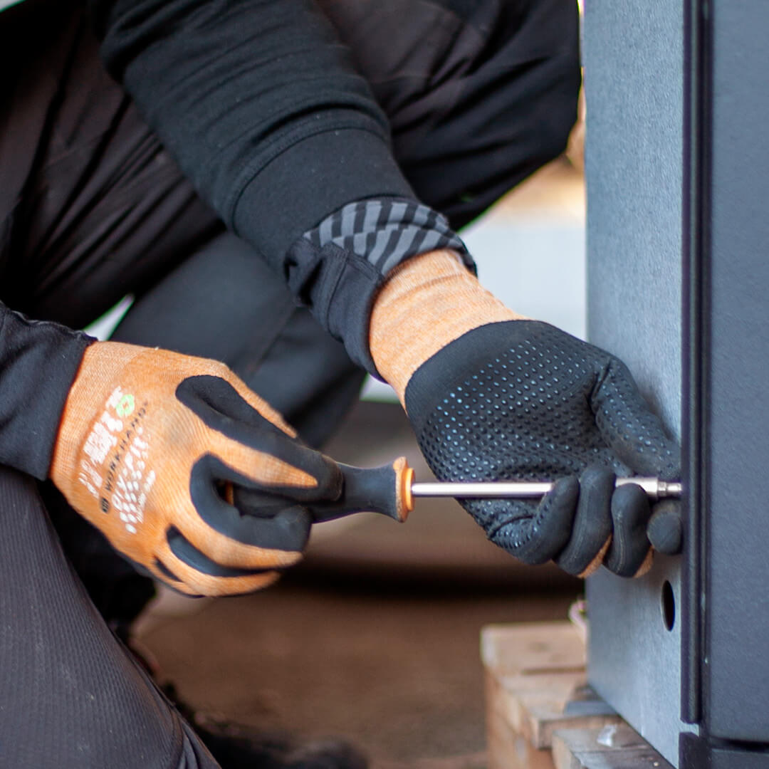 Hands turning a screw in a wood stove