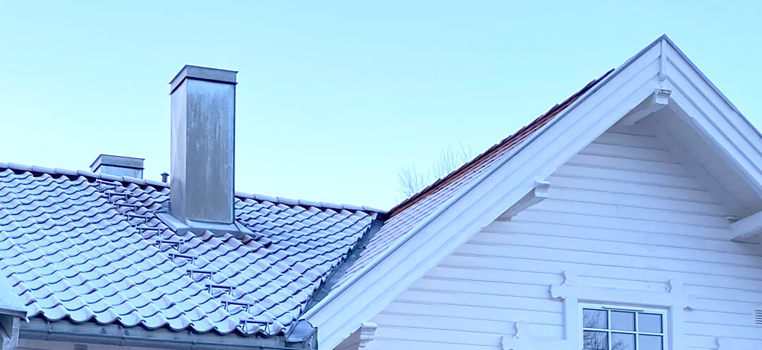 Roof and chimney of a white house on a cold winter's day