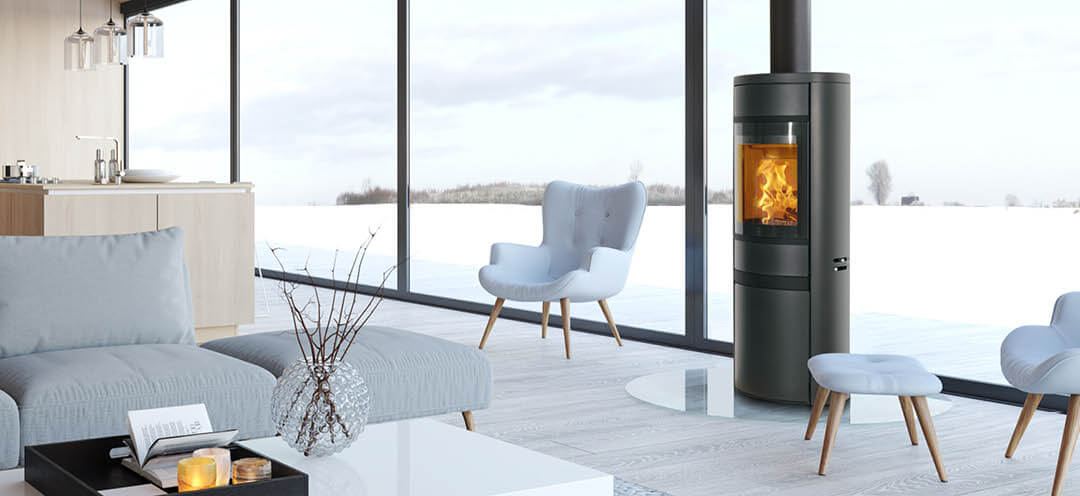 Black oval wood-burning stove Scan 68-13 in a modern living room with bright furniture and large windows facing a snowy landscape