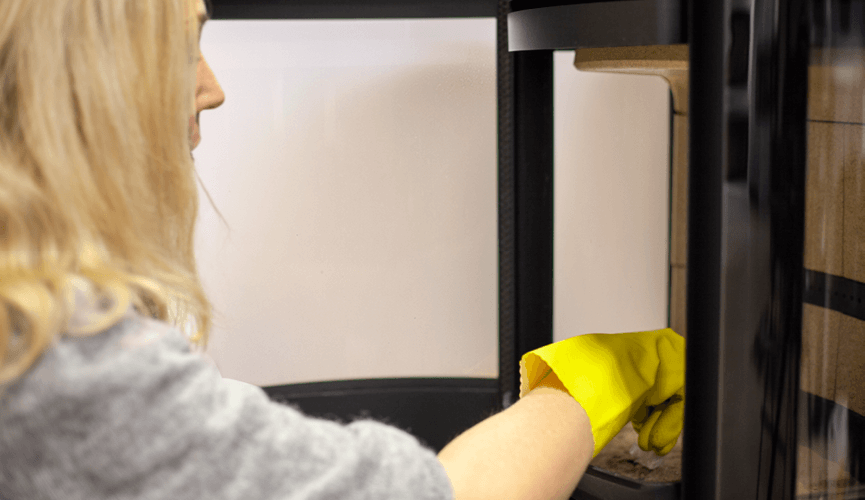 Woman with yellow rubber gloves clean ash from the fireplace