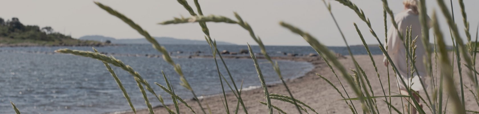 Woman in white dress walking along a Danish beach
