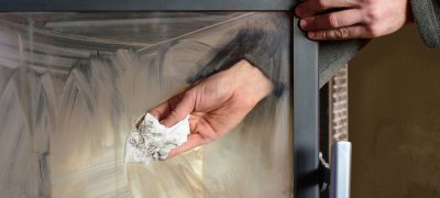 The hand cleaning a dirty fireplace glass