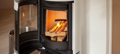 White wood-burning stove Scan 83-2 with open door and fire that is lit