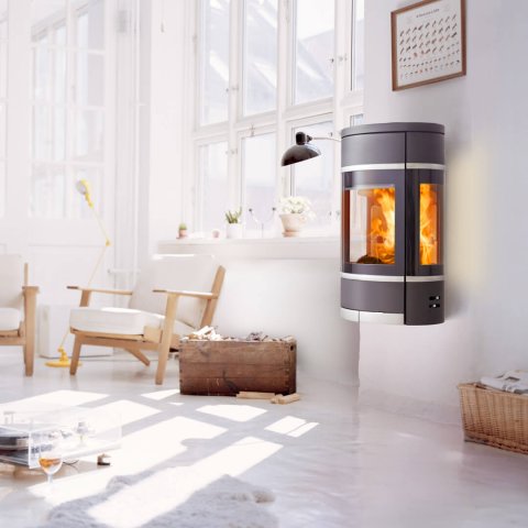 Oval Scan 68 wood stove hanging on the wall by a large window in a white living room with light wooden furniture